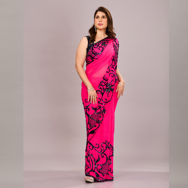 A vibrant pink saree with black embroidered floral and vine patterns