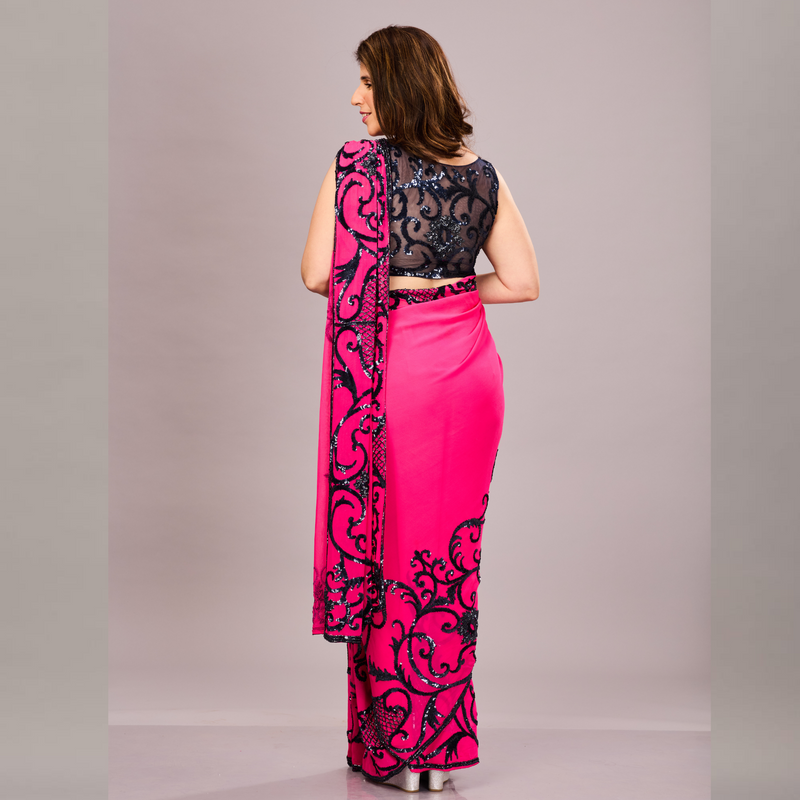 A vibrant pink saree with black embroidered floral and vine patterns