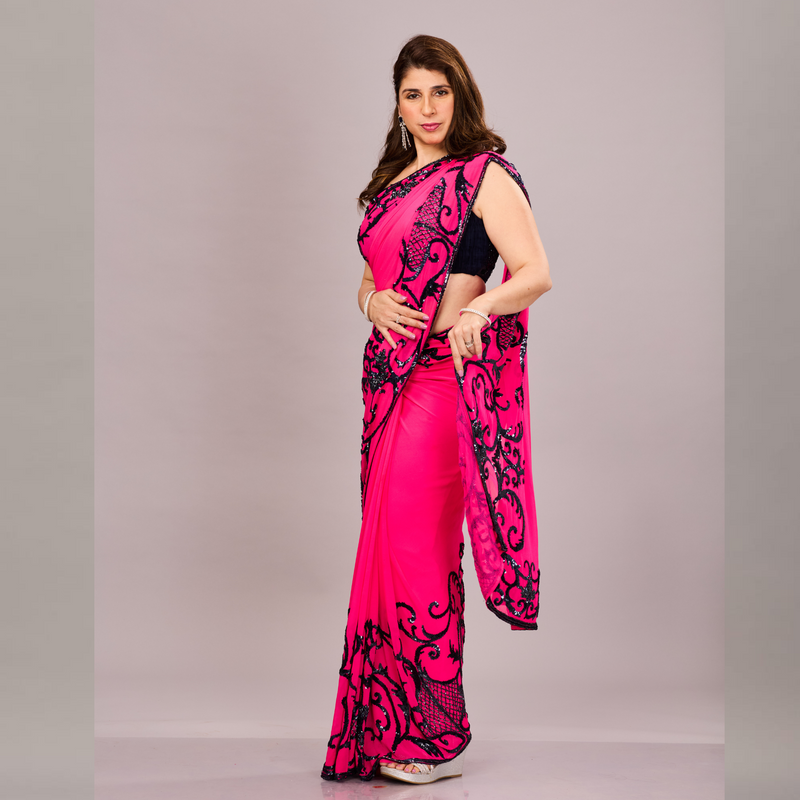 A vibrant pink saree with black embroidered floral and vine patterns