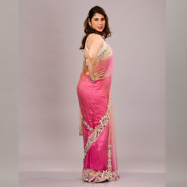 gracefully draped in a pink and orange shaded net saree with ornate white and gold embroidery