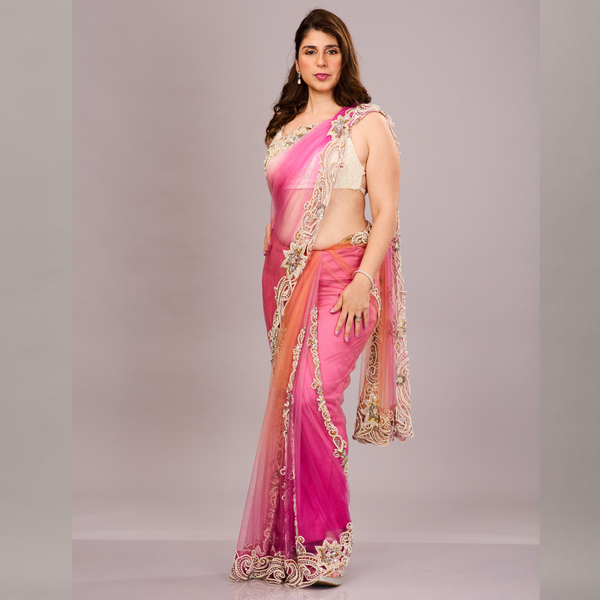 gracefully draped in a pink and orange shaded net saree with ornate white and gold embroidery