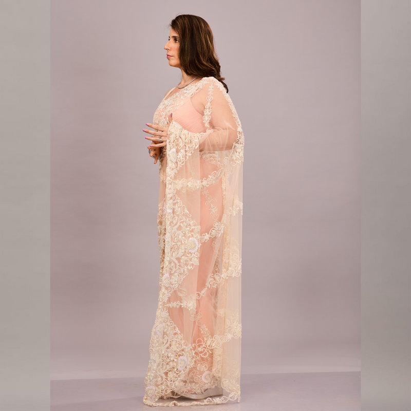 pastel peach net saree with intricate ivory floral embroidery and a matching sleeveless blouse