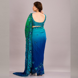 A vibrant green and blue embroidered saree with floral embellishments and sheer fabric
