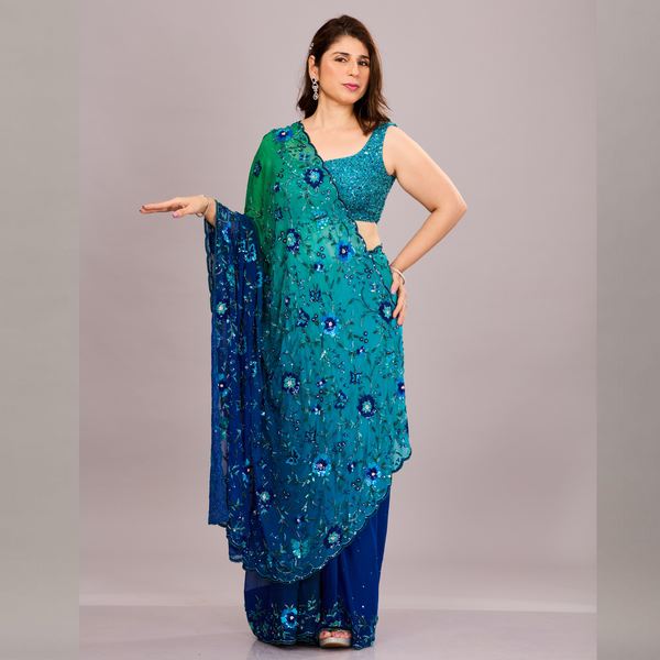 A vibrant green and blue embroidered saree with floral embellishments and sheer fabric