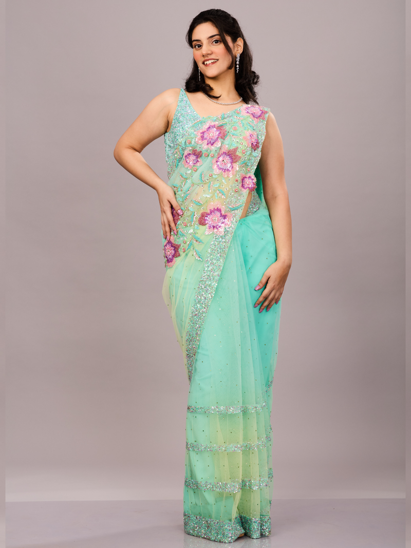 Mint green net saree adorned with sequin borders and paired with a floral embroidered blouse.