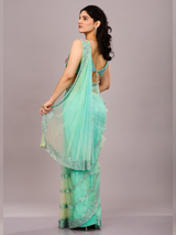 Mint green net saree adorned with sequin borders and paired with a floral embroidered blouse.