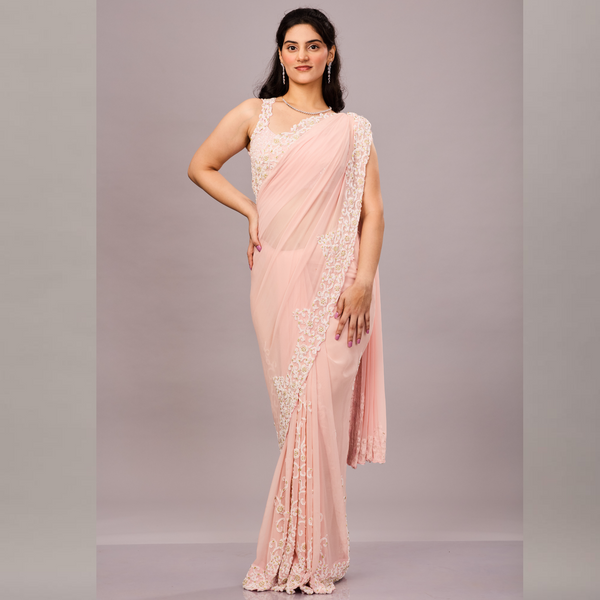 A pastel pink saree with delicate white floral embroidery along the border