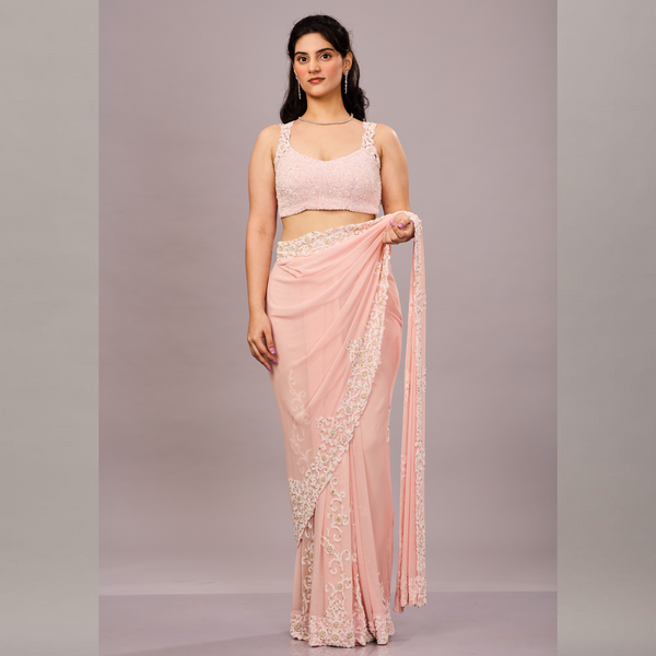 A pastel pink saree with delicate white floral embroidery along the border