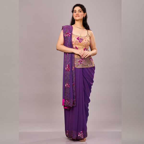 A deep purple saree with embellished borders paired with a beige floral embroidered sleeveless blouse.