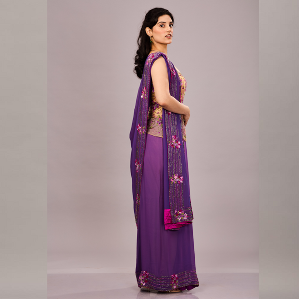 A deep purple saree with embellished borders paired with a beige floral embroidered sleeveless blouse.